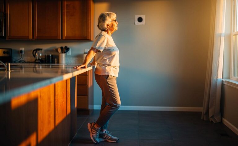 Illustration von einer älteren Person im Tandemstand, die eine Blickstabilisationsübung mit fixiertem Zielpunkt neben einer stabilen Stütze ausführt